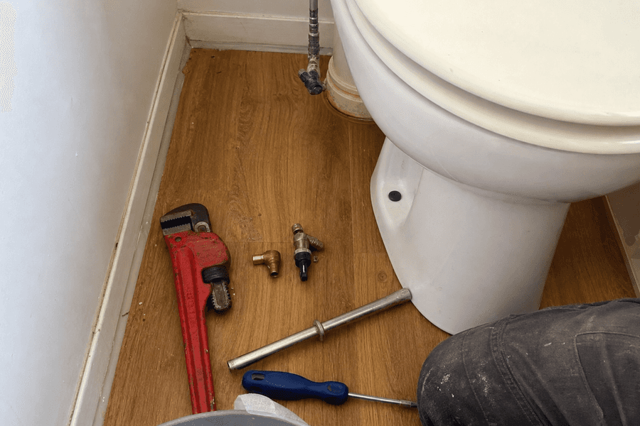outillage de plombier posé près d'une cuvette de WC